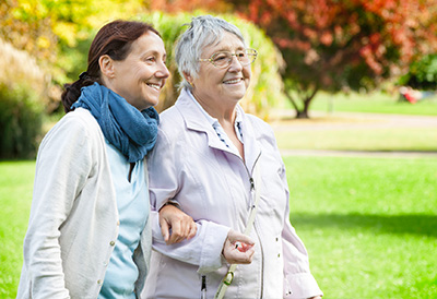 Dementia-Alzheimers Care A middle aged woman arm in arm with an older woman