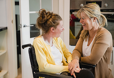 Disability Care Woman laughs with a younger woman in a wheelchair