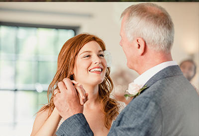 Family Events A bride and father of the bride dance while smiling